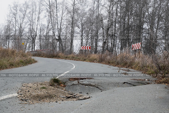 Pothole damage on a rural road surrounded by trees in autumn highlights urgent need for repairs. Стоковое фото, фотограф Георгий Мякишев / Фотобанк Лори