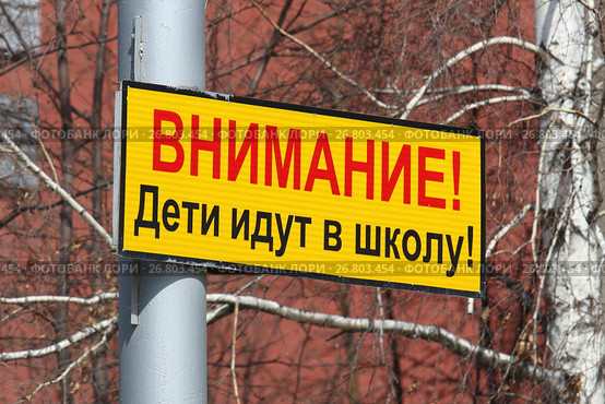 Предупреждающая табличка на столбе с надписью "Внимание! Дети идут в школу!" над проезжей частью улицы в городе Новосибирске (2017 год). Стоковое фото, фотограф Григорий Писоцкий / Фотобанк Лори