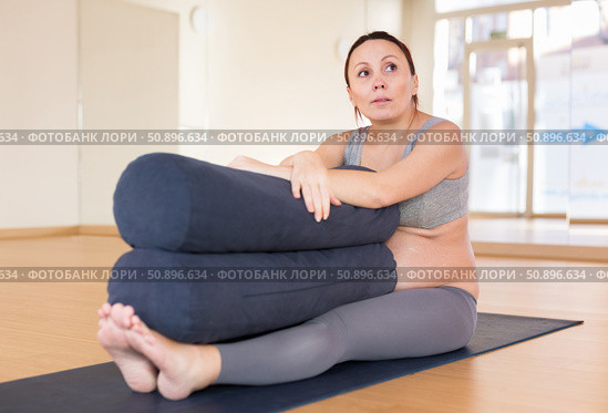 pregnant woman practices yoga with roll in hall. Стоковое фото, фотограф Татьяна Яцевич / Фотобанк Лори
