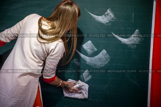 Преподаватель учит людей писать буквы на доске древнего восточного языка санскрита (2023 год). Редакционное фото, фотограф Николай Винокуров / Фотобанк Лори