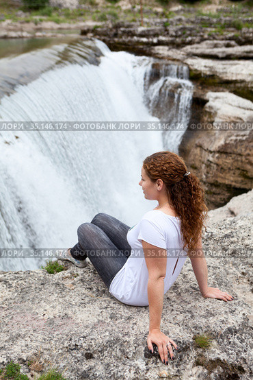 Pretty woman sitting on rock and enjoying of the cascade of Cijevna river. It is called Montenegrin Niagara Falls. Surroundings of Podgorica city. Montenegro, Balkans, Europe. Стоковое фото, фотограф Кекяляйнен Андрей / Фотобанк Лори