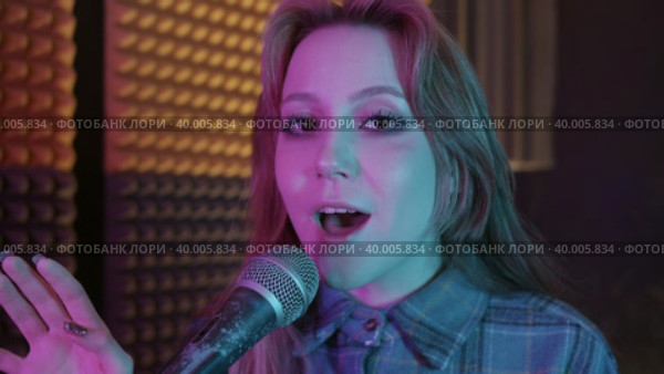 Pretty woman wearing winged eyeliner walks closer to the camera and starts to sing in the mic. Стоковое видео, видеограф Константин Шишкин / Фотобанк Лори