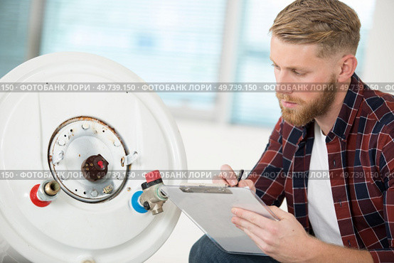 professional electrician man is fixing a water heater. Стоковое фото, агентство Ingram Publishing / Фотобанк Лори