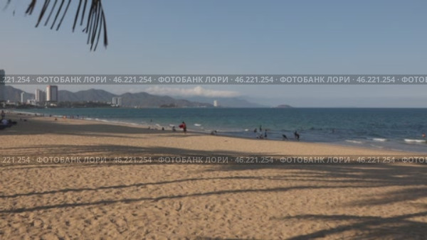 Public beach in Nha Trang, Vietnam. Beautiful view of the embankment, mountains, beach and South China Sea. Tourists and locals relax and swim. Handheld shooting in slow motion. Overview. Стоковое видео, видеограф Наталья Любина / Фотобанк Лори