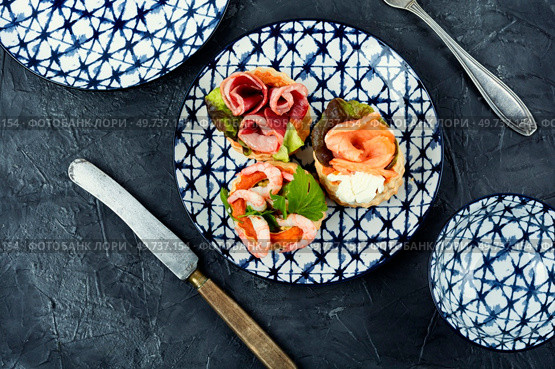 Puff pastry tartlets or canapes with fish, shrimp and bacon on a plate on the table.. Tartlets with seafood and bacon, tasty snack. Стоковое фото, агентство Ingram Publishing / Фотобанк Лори