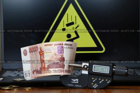 Пятитысячные купюры и цифровой микрометр на фоне знака "Осторожно, возможно падение предметов с высоты" (2024 год). Редакционное фото, фотограф Сергей Шелагин / Фотобанк Лори