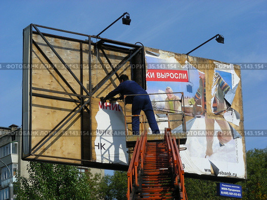 Рабочие-монтажники закрепляют стритбаннер на опоре. Улица Ленина. Город Реутов. Московская область (2012 год). Редакционное фото, фотограф lana1501 / Фотобанк Лори
