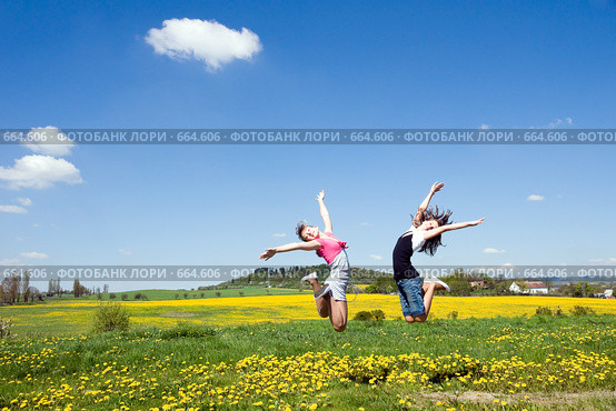 Радостные девочки прыгают в цветущем поле. Стоковое фото, фотограф Ирина Игумнова / Фотобанк Лори
