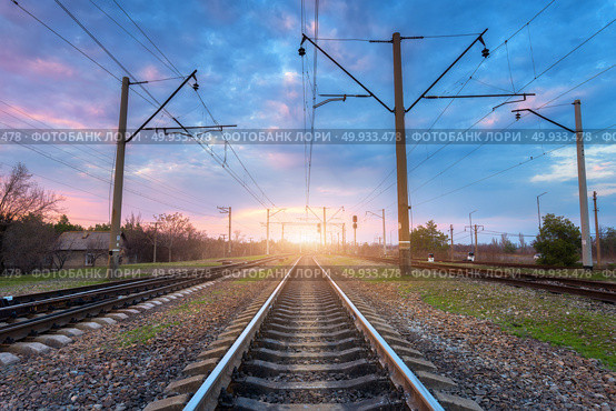 Railroad and beautiful sky at sunset. Industrial landscape with railway station, colorful blue sky with clouds, trees and green grass, yellow sunlight in summer. Railway junction. Heavy industry. Railroad and beautiful sky at sunset. Railway. Стоковое фото, агентство Ingram Publishing / Фотобанк Лори