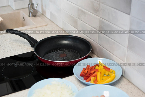 Растительное масло разогревается на сковородке, рядом с которой приготовлены к жарке нарезанные овощи. Стоковое фото, фотограф Алиса Сокол / Фотобанк Лори