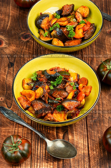 Ratatouille or stewed potatoes, eggplants, zucchini, onions, carrots in spicy sauce with greens. Rustic style.. Delicious vegetable stew in a bowl on the table. Стоковое фото, агентство Ingram Publishing / Фотобанк Лори