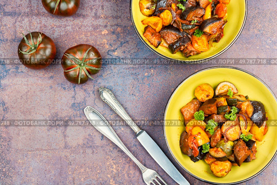 Ratatouille or stewed potatoes, eggplants, zucchini, onions, carrots in spicy sauce with greens. Space for text.. Delicious vegetable stew in a bowl on the table. Стоковое фото, агентство Ingram Publishing / Фотобанк Лори