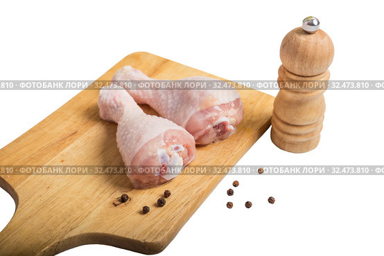 Raw chicken legs on cutting board and peppercorns with pepper mill. Isolated on white background. Стоковое фото, фотограф Юлия Бабкина / Фотобанк Лори