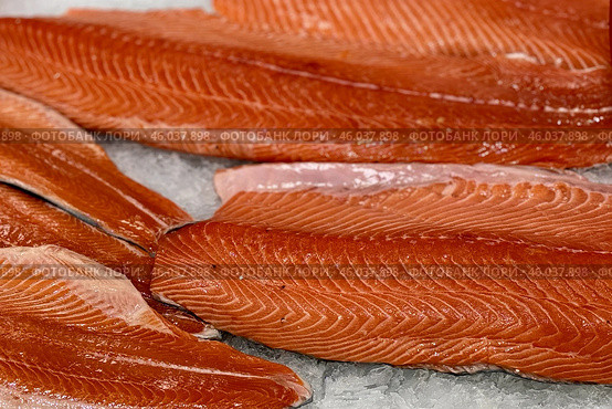 Raw fresh layers of Atlantic salmon lie on shallow ice at the seafood market. An open shelf at the fish market. Стоковое фото, фотограф worker / Фотобанк Лори
