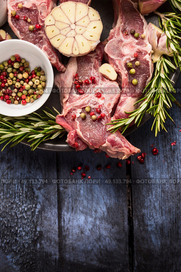 Raw lamb meat with peppercorn, rosemary and garlic on blue rustic wooden table, place for text. Стоковое фото, агентство Ingram Publishing / Фотобанк Лори