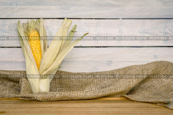 Raw maize cob on a wooden table. Стоковое фото, агентство Ingram Publishing / Фотобанк Лори