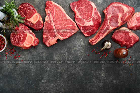 Raw prime steaks. Variety of fresh black angus prime meat steaks T-bone, New York, Ribeye, Striploin, Tomahawk on black or gray stone background. Set of various classic steaks. Top view, copy space. Стоковое фото, агентство Ingram Publishing / Фотобанк Лори
