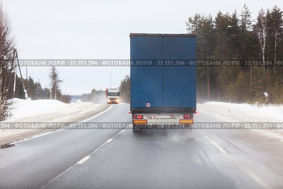 Rear view at semitrailer truck driving on slippery winter road in northern forests. Стоковое фото, фотограф Кекяляйнен Андрей / Фотобанк Лори