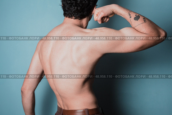Rear view of a muscular young man flexing his arm. Стоковое фото, агентство Ingram Publishing / Фотобанк Лори