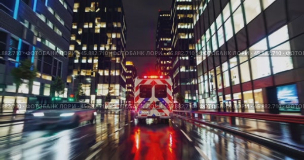 Rear view of an ambulance with flashing lights speeding through a city at night. Стоковое AI-видео, аниматор Александр Довянский / Фотобанк Лори