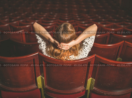 Rear view shot of a young woman sitting alone in an auditorium. Стоковое фото, агентство Ingram Publishing / Фотобанк Лори