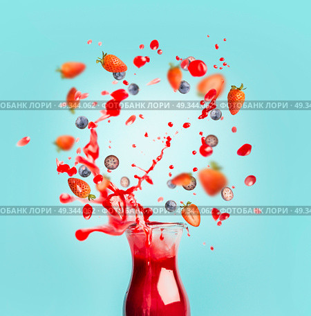 Red juice or smoothie drink is poured out of glass bottle with splash and berries ingredients on turquoise background, front view. Healthy summer beverage concept. Стоковое фото, агентство Ingram Publishing / Фотобанк Лори