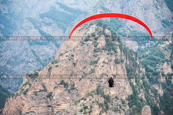 red paraglider flies against the background of mountains, rear view. Стоковое фото, фотограф Александр Довянский / Фотобанк Лори