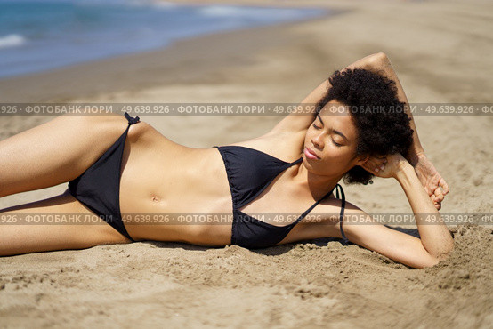 Relaxed African American female lying on the sand of a tropical beach sunbathing. Black girl tanning.. Relaxed African American female lying tanning on the sand of a tropical beach sunbathing. Стоковое фото, агентство Ingram Publishing / Фотобанк Лори