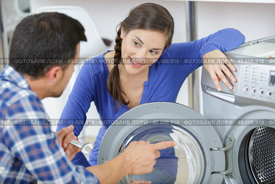 repairman repairing washer in front of woman. Стоковое фото, агентство Ingram Publishing / Фотобанк Лори