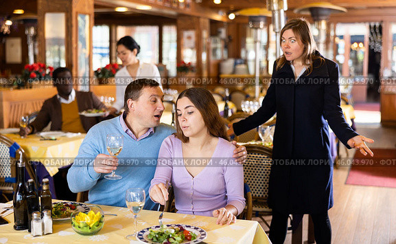 Resentful wife scolding her husband spending time with another woman at dinner. Стоковое фото, фотограф Яков Филимонов / Фотобанк Лори