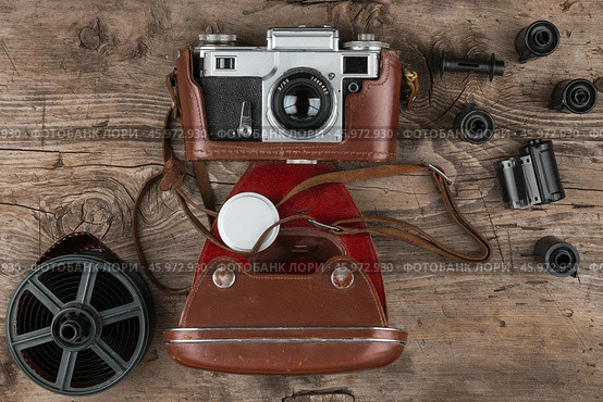 Retro camera in a brown leather case lies on a wooden table. Top view. Стоковое фото, фотограф Александр Собко / Фотобанк Лори