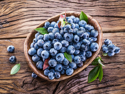 Ripe blueberries in the bowl on the wooden table. Стоковое фото, агентство Ingram Publishing / Фотобанк Лори