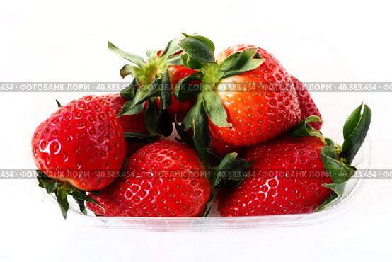 Ripe strawberries in a plastic package on a white background. Delicious fresh berries in a container for sale to customers. Keeping food fresh. Healthy food, vitamins and microelements. Стоковое фото, фотограф Юлия Петровская / Фотобанк Лори