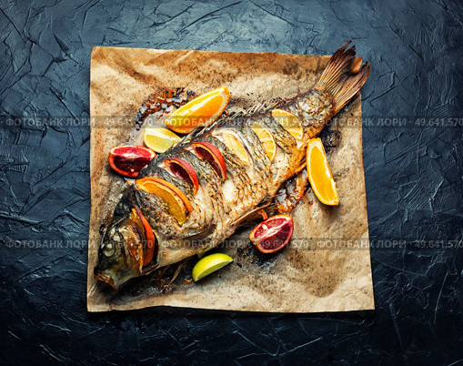 River fish carp grilled whole with lemon and oranges.. Appetizing baked carp. Стоковое фото, агентство Ingram Publishing / Фотобанк Лори