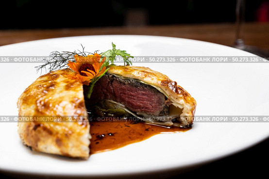 Roasted Beef Wellington with gravy brown savory sauce, international gourmet cuisine of stuff beef meat in baked bread puff. Unising for recipe menu pf food and drink industry.. roasted beef wellington. Стоковое фото, агентство Ingram Publishing / Фотобанк Лори