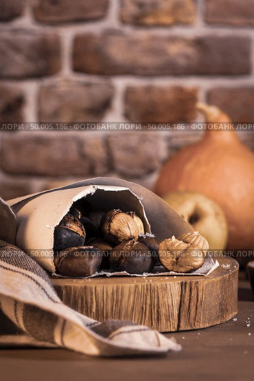 Roasted chestnuts in a paper cone, on a rustic kitchen countertop. Стоковое фото, агентство Ingram Publishing / Фотобанк Лори