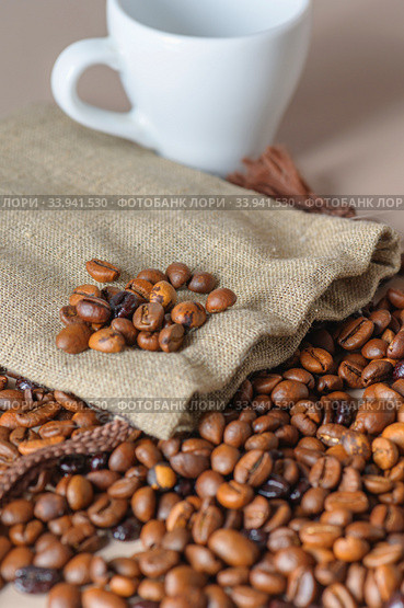 Roasted coffee beans, a white Cup, and a small burlap bag in close-up. Roasted coffee beans of the morning mood. Стоковое фото, фотограф Artem Sobov / Фотобанк Лори