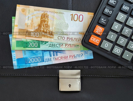 Российские деньги, калькулятор лежат на черном офисном портфеле. Стоковое фото, фотограф Цибаев Алексей / Фотобанк Лори