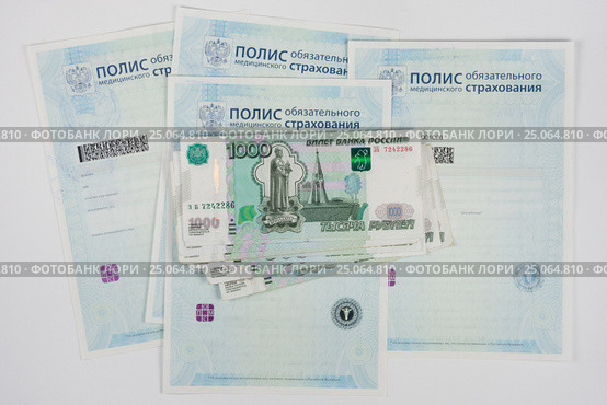 Российские деньги лежат на полисах обязательного медицинского страхования, белый фон. Стоковое фото, фотограф Иванов Алексей / Фотобанк Лори