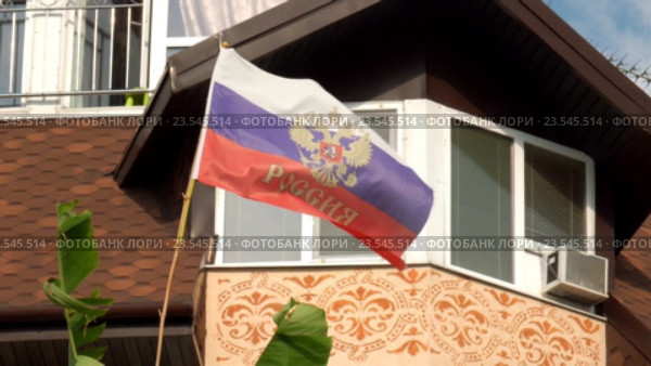 Российский флаг с гербом и надписью "Россия" развевается на фоне фасада дома (2016 год). Стоковое видео, видеограф Александр Замараев / Фотобанк Лори