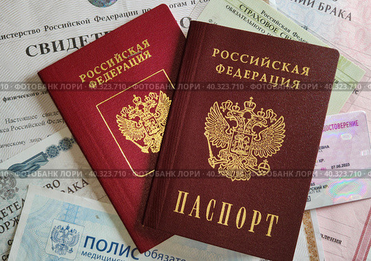 Российский паспорт и загранпаспорт на стопке личных документов гражданина. Гражданский и заграничный паспорта, СНИЛС, свидетельства о заключении и расторжении брака, ИНН, медицинский полис и водительское удостоверение. Russian passport and a foreign passport on a stack of personal documents of a citizen. Inscriptions on documents in Russian. Medical insurance policy, driver's license, pension certificate, TIN. Стоковое фото, фотограф Ирина / Фотобанк Лори
