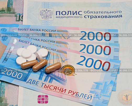 Российский полис обязательного медицинского страхования, денежные купюры и лекарства в таблетках (2021 год). Редакционное фото, фотограф Цибаев Алексей / Фотобанк Лори