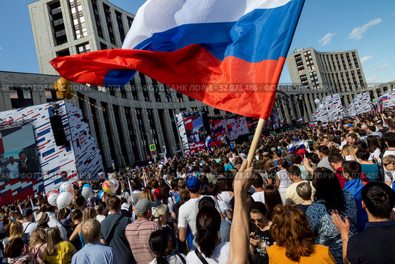 Российский триколор развевается над толпой во время митинга-концерта в честь Дня российского флага на проспекте Сахарова.в городе Москве, Россия (2019 год). Редакционное фото, фотограф Николай Винокуров / Фотобанк Лори