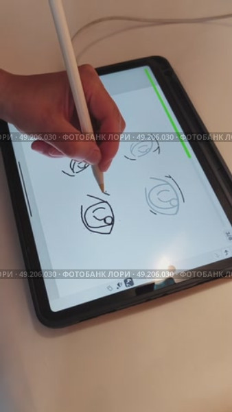 Рука девушки креатора держит пальцами pensil и рисует на планшете ipad pro изображение глаза человека в специальной программе для обучения художников для инстаграм и тик ток. Стоковое видео, видеограф Светлана Русских / Фотобанк Лори