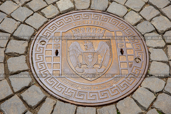 Румыния. Бухарест. Крышка люка на мощеной мостовой. Romania. Bucharest. A manhole cover on a paved pavement. Стоковое фото, фотограф Алексей Смышляев / Фотобанк Лори