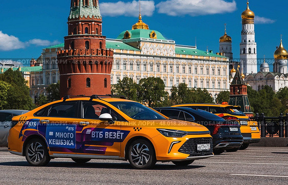 Russia, Moscow, April 28, 2025. Taxi business. A yellow taxi car in motion against the background of the Kremlin in the center of the capital. A trip to the famous sights of Moscow. Редакционное фото, фотограф Photojuli / Фотобанк Лори