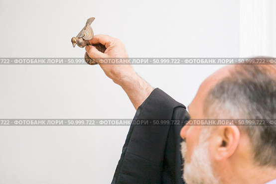 Russia, Rostov-on-Don - May 30, 2014: An Armenian priest holds a bird figurine in his hand and performs the rite of baptism over the font. Редакционное фото, фотограф Екатерина Красникова / Фотобанк Лори