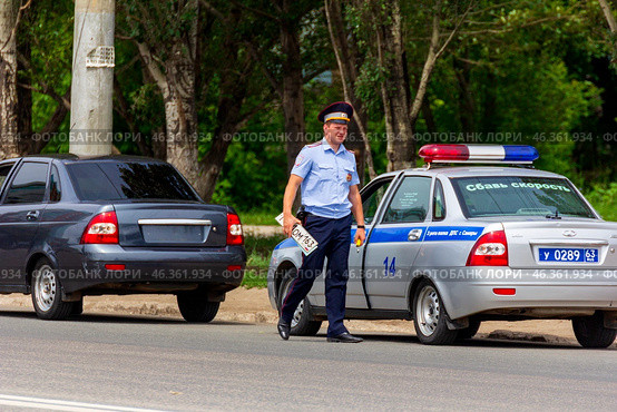 Russia, Samara. June 22, 2014. A traffic police inspector removed a license plate from a car for violating traffic rules on a sunny summer day. Text in Russian:police slow down. Редакционное фото, фотограф Акиньшин Владимир / Фотобанк Лори