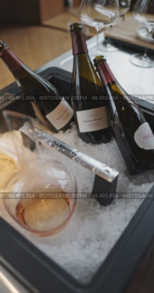 Russia, St.Petersburg, 24 April 2025: Several bottles of champagne brand Bonnet-Ponson are cooled in a niche with ice in the restaurant, local lighting, wine cabinet, decanters for sparkling wine. Редакционное видео, видеограф Vladimir Drozdin / Фотобанк Лори