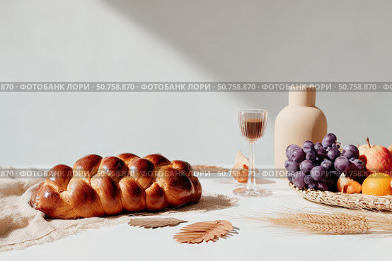 Rustic autumn table: challah bread, grapes, apples, and wine with natural decor. Стоковое AI-изображение, AI-художник Мария Фадеева / Фотобанк Лори